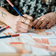 Faceless illustrator coloring clothing sketch with pencil on paper